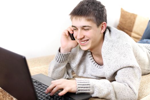 happy teenager with notebook talking on mobile phone in home interior