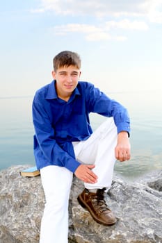 happy young man sitting near the water
