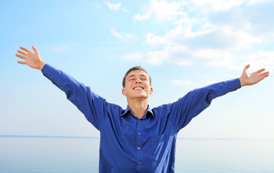 happy young man spread hands on the seaside background in the sunny day