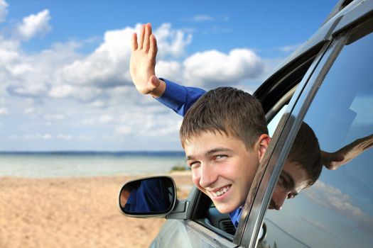 happy young man sitting in the car and wave goodbye