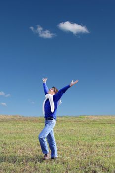 happy young man raising his hands in the summer field