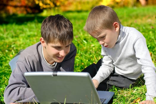 teenager and kid with notebook on the meadow