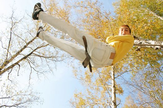 Young and happy teenager jumping on the bungee in the autumn forest