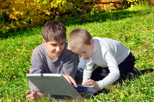 teenager and kid with notebook on the meadow