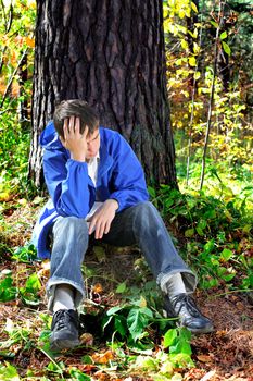 sorrowful teenager sitting in the autumn forest alone