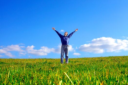 happy young man raising his hands in the summer field