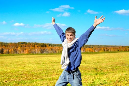 happy teenager with hands up in the autumn field