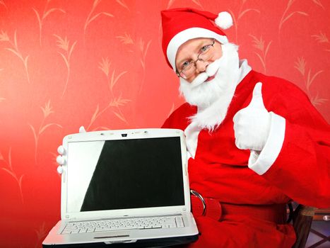 santa claus with laptop computer with empty screen on the red wall background