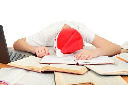 tired student in santa's hat sleeping on school desk after hard work for exam