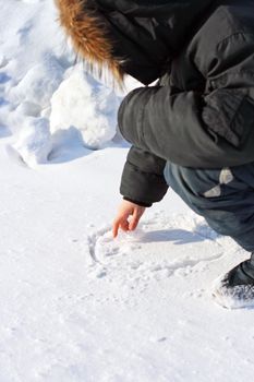 Boy Draws on the Snow in Winter