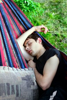 Young Man sleeping in the Hammock on the Nature