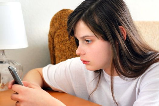 Sad Teenage Girl with Mobile phone at the Home