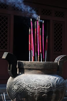 Burning incense sticks in front of a traditional Chinese ancient temple