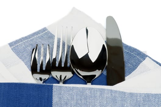 Arrangement of Silverware with Table Knife, Spoon, Fork and Dessert Fork under Blue Napkin isolated on white background