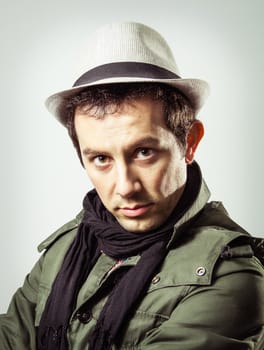 Portrait of handsome trendy young man wearing hat and scarf on grey background