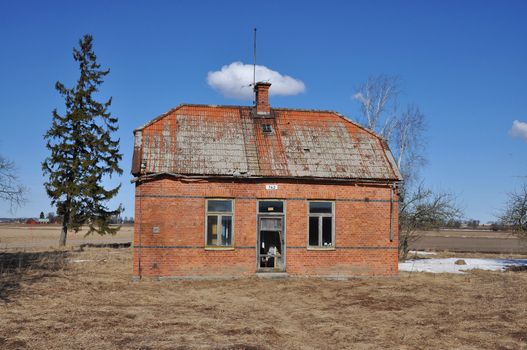 Condemned brick building falling apart on a field.