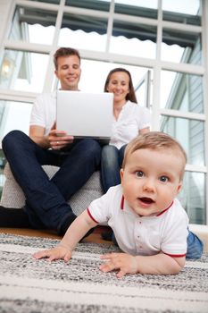 Portrait of cute child with parents using laptop in the background