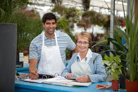 Young male with senior woman working in a garden center