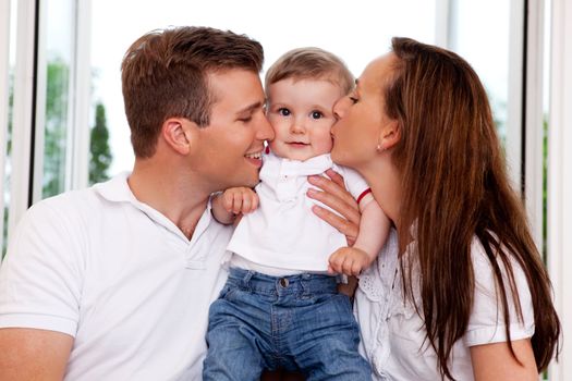 Mother and Father kissing their toddler son on the cheek