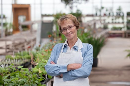 Portrait of smiling senior female worker standing with arms crossed