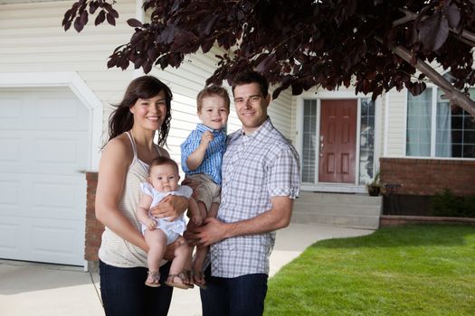 Portrait of sweet family standing in front of their house