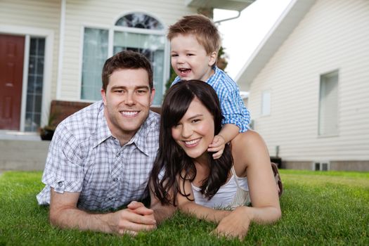 Portrait of cheerful family lying down on grass in front of house