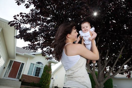 Happy mother holding up her adorable daughter