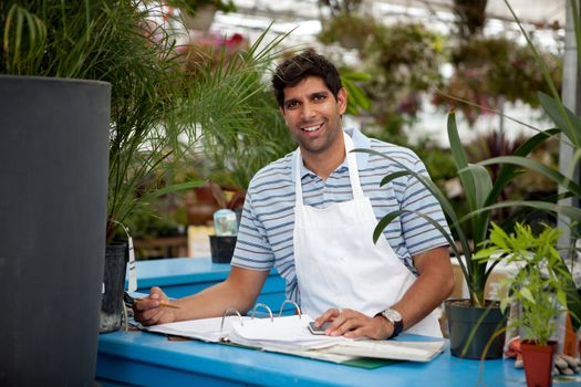 Young male garden center employee at check out counter