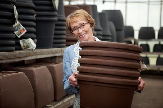 Portrait of a senior worker in garden center with large plant pots