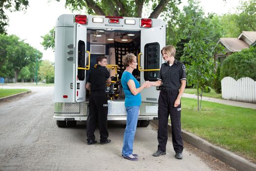 Elderly woman thanking ambulance staff for help