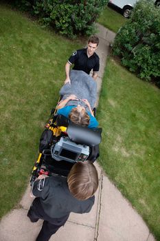 Overhead view of emergency medical team pushing senior woman on stretcher.  Shallow DOF sharp focus on patient