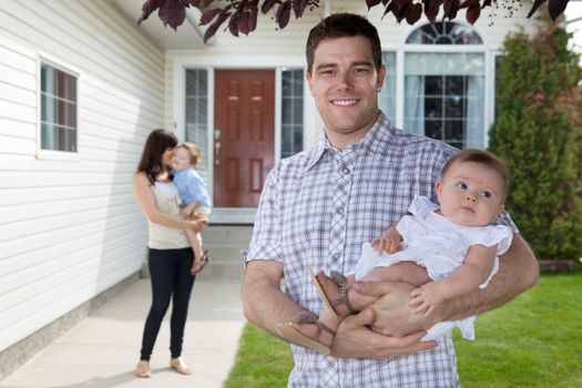 Portrait of man holding his daughter with wife standing behind holding son