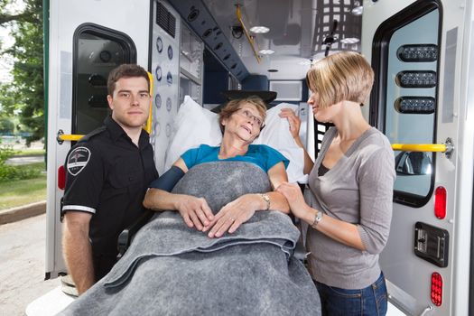 Senior woman being taken on ambulance, daughter at side