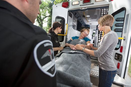 Senior woman being loaded onto ambulance with caregiver at side