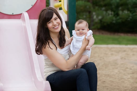 Mother sitting with her adorable daughter in playground