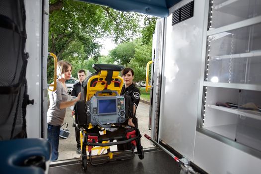 Emergency team loading patient in ambulance, caregiver at side