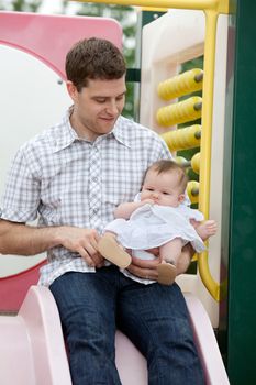 Father sitting on slide with his adorable daughter