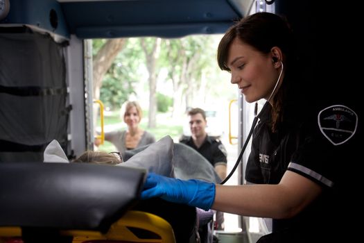 Paramedic listening to heart rate of patient in ambulance