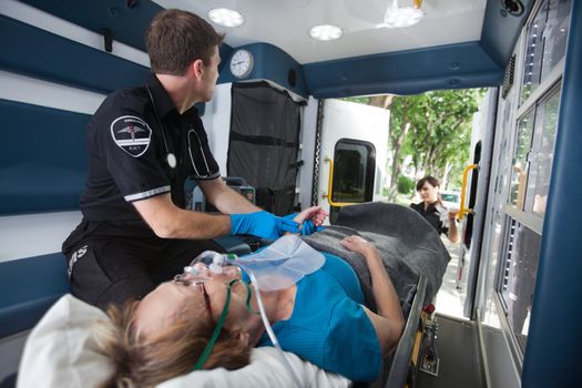 EMT professional check pulse on elderly woman in ambulance