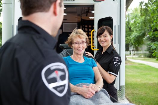 Two ambulance workers pushing a happy femaile patient