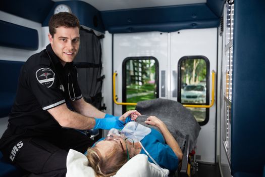 Portrait of a male EMT inside ambulance with senior woman patient