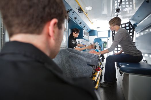 Emergency medical team tends to a senior woman patient, caregiver at side