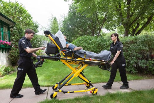 Senior woman on emergency medical stretcher being transported from home