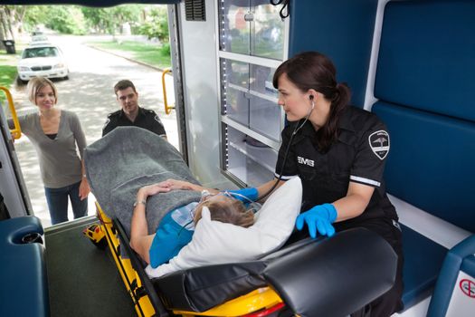 Young woman looking into ambulance at senior woman