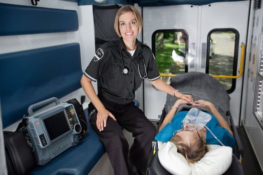 Female EMT professional in ambulance with senior woman patient