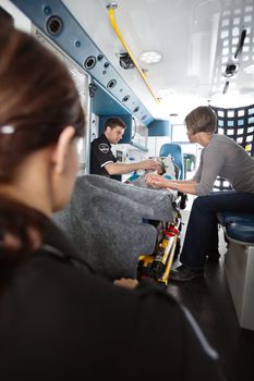 Elderly woman in ambulance being given oxygen, caregiver at side