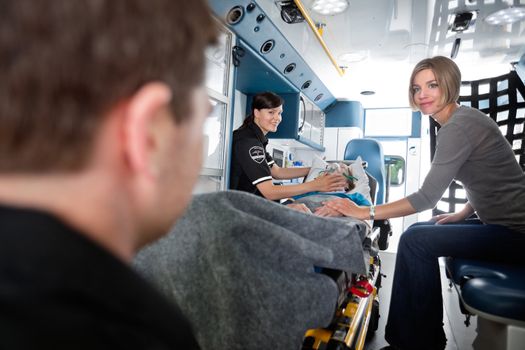 EMT professionals caring for an elderly patient with caregiver at side.