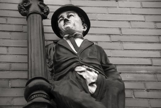 Figure of actor Charlie Chaplin with bowler hat, wall in background