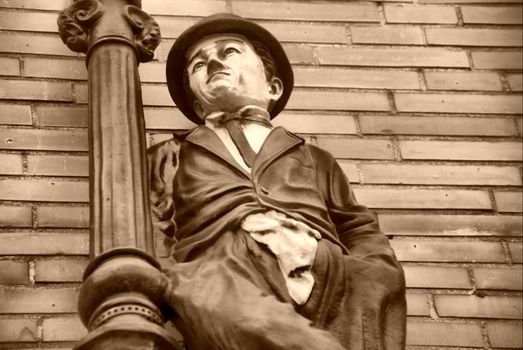 Figure of actor Charlie Chaplin with bowler hat, wall in background