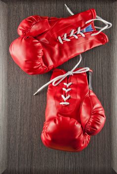 Red boxing gloves over wooden dark background